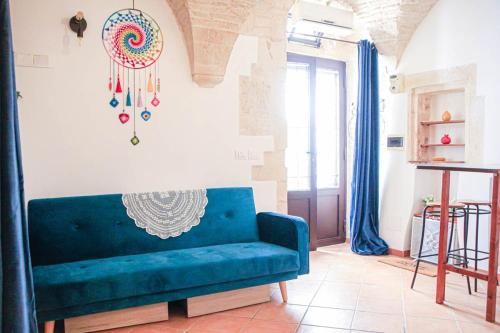 a living room with a blue couch and a wall at Meta di Puglia - Almalusa Apulian Home by In Puglia service in Martina Franca