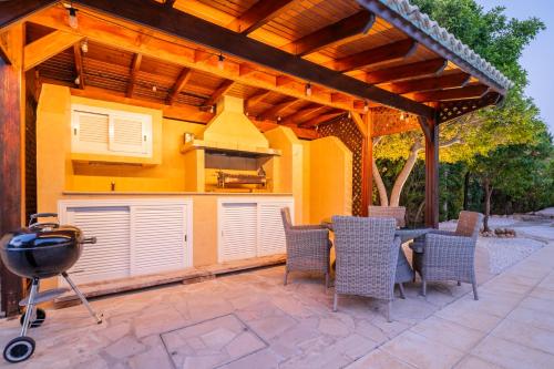 a patio with a grill and a table and chairs at Villa Pontus - stunning views & privacy in beautiful garden with pool & hot tub in Kouklia