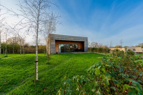 a house in a field with a tree at Cosy Cabin Getaway - Ashbourne in Ashbourne