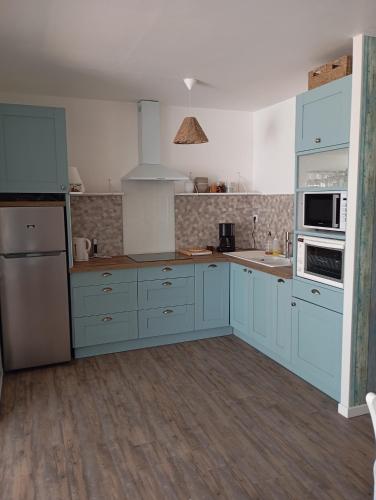 une cuisine avec des armoires bleues et des appareils blancs dans l'établissement Maison St jean de monts 500 m de la plage, à Saint-Jean-de-Monts