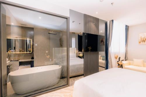a white bathroom with a tub and a bedroom at New Century Dalat Hotel in Da Lat