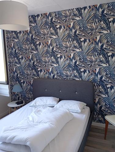 Ce lit se trouve dans une chambre dotée d'un papier peint bleu et blanc. dans l'établissement Maison St jean de monts 500 m de la plage, à Saint-Jean-de-Monts