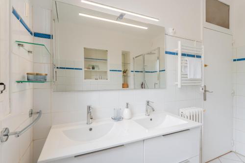 une salle de bain blanche avec un lavabo et un miroir dans l'établissement Le Prestige - Au cœur de Nantes, à Nantes