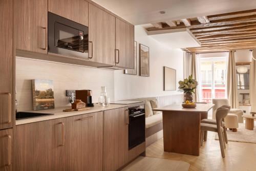 une cuisine avec des placards en bois, une table et un comptoir dans l'établissement chic A C central apt - 2bdr 6p - faubourg s denis, à Paris