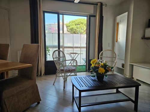un salon avec une table avec un vase de fleurs dessus dans l'établissement 3 pièces à 50 m de la plage, à Fréjus