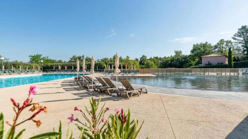 une piscine avec des chaises longues et une fontaine dans l'établissement Village Le Rouret - maison avec piscines partagées, à Grospierres