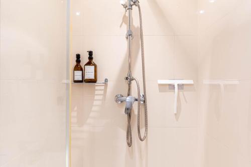 La salle de bains est pourvue d'une douche avec 2 bouteilles de vin. dans l'établissement Chambre au calme près du Père-Lachaise, à Paris