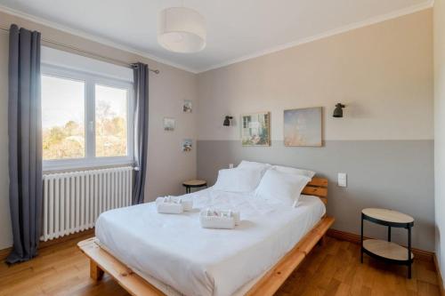 une chambre avec un grand lit blanc avec deux tables dans l'établissement Maison ensoleillée et conviviale, à Lancieux