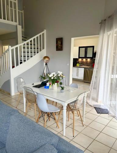 une salle à manger avec une table et des chaises blanches dans l'établissement Maison calmer & confort, au Mans