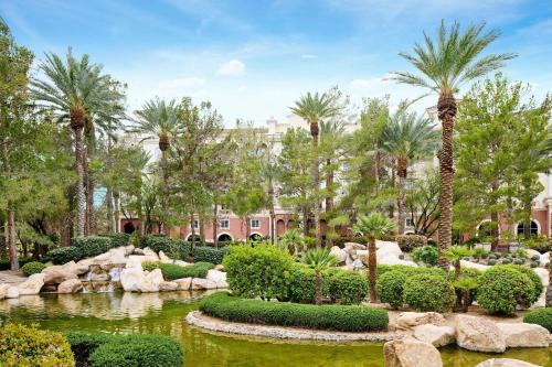 a garden with palm trees and a pond in front of a building at JW Marriott Las Vegas Resort & Spa in Las Vegas