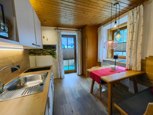 una piccola cucina con tavolo rosso in una stanza di Haus Groder a Rauris
