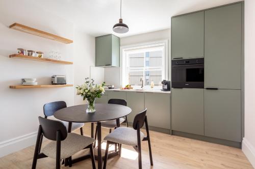 a kitchen with a table and chairs and a kitchen with green cabinets at Marlin Westminster Apartments in London