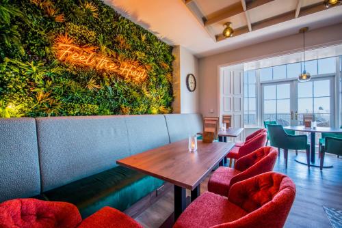 a restaurant with a green wall with a wooden table and chairs at Imperial Hotel Tenby in Tenby