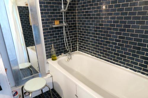 La salle de bains est pourvue d'une baignoire blanche et de carrelage bleu. dans l'établissement Beau 4 pièces dans coin de verdure, à Paris