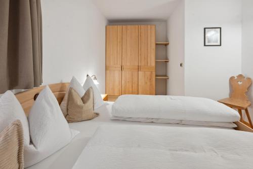 two beds in a bedroom with white sheets and pillows at Prackfolerhof in Fie allo Sciliar
