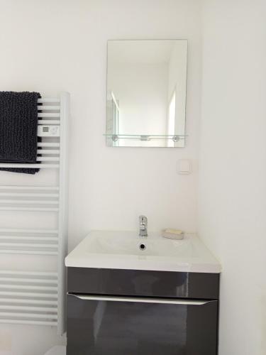 a white bathroom with a sink and a mirror at Studio paisible avec vue sur les coteaux 