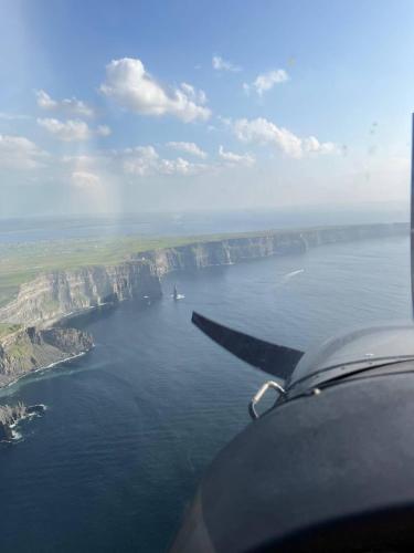 a wing of an airplane flying over a body of water at Dun Aengus Cottage on the Cliffs of Moher in Liscannor