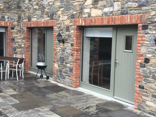 a stone building with a door and a patio at Beautiful 3 Bed House, Sleeps 5 - No 4 Lyrath in Ashbourne