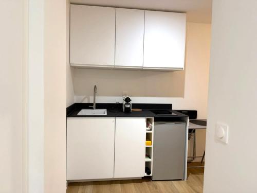 une cuisine avec des armoires blanches et un évier dans l'établissement M11 Marquer Studio le Clos Fleury, à Annemasse