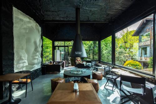 a room with tables and chairs and large windows at 阅时 Adonis野生派 Black Bar 森林大院民宿 in Lijiang