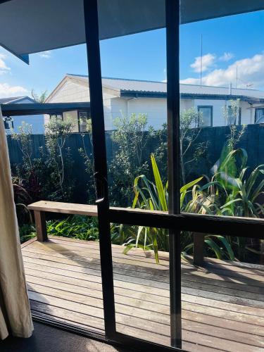 Cette chambre offre une vue sur une terrasse dotée d'un banc à travers une fenêtre. dans l'établissement Private room in sunny Bayfair, à Mount Maunganui