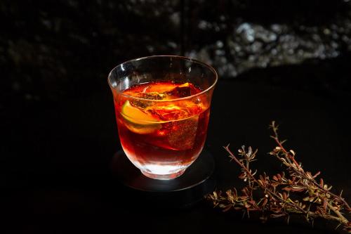a drink in a glass sitting on a table at 阅时 Adonis野生派 Black Bar 森林大院民宿 in Lijiang