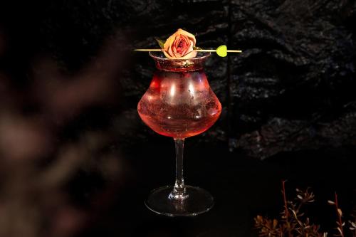a drink with a rose in a wine glass at 阅时 Adonis野生派 Black Bar 森林大院民宿 in Lijiang