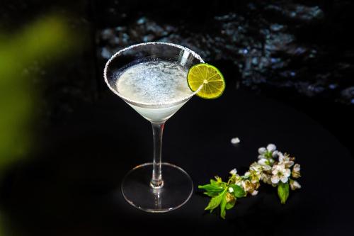 a martini glass with a lime on a table at 阅时 Adonis野生派 Black Bar 森林大院民宿 in Lijiang