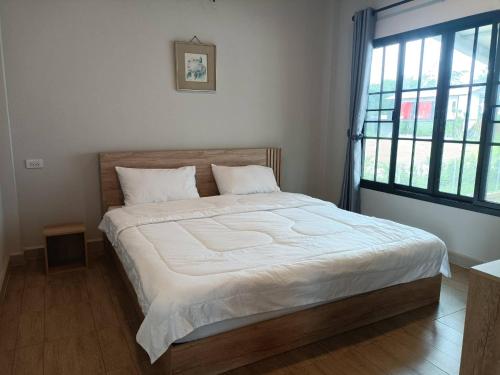 a bed in a bedroom with a large window at เชียงรายฟิวชั่น in Ban Pa Faek