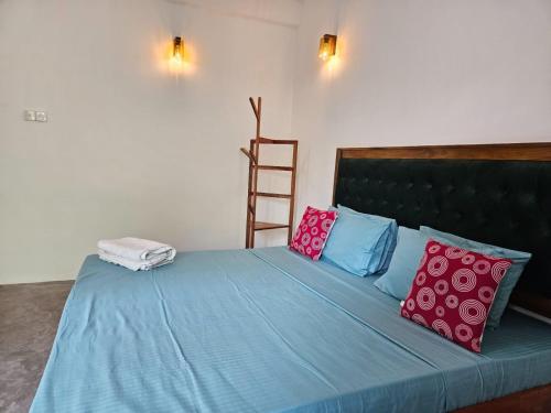 a bed with blue sheets and colorful pillows on it at THE HIDEOUT KURUNEGALA in Kurunegala