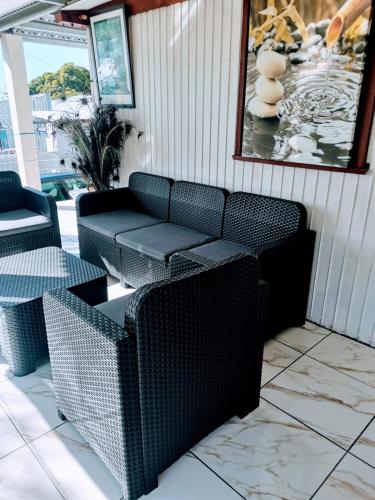 a patio with wicker chairs and a couch at Feunteun Veur in Saint-Paul