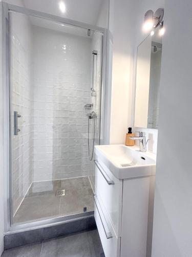 une salle de bain blanche avec une douche et un lavabo dans l'établissement L'Atelier Bordelais - Centre Ville - Elégant, à Bordeaux