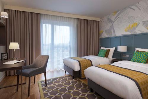 a hotel room with two beds and a desk at Citadines City Centre Frankfurt in Frankfurt/Main