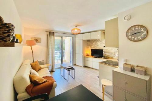 un salon avec un canapé et une horloge au mur dans l'établissement Bright apartment for 4 - near beach, à Saint-Raphaël