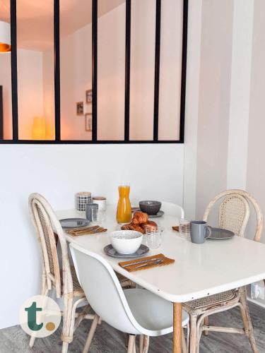 une table à manger avec des chaises et une table blanche avec de la nourriture. dans l'établissement Tranquiloue - Studio Plein Centre - Puy du Fou 20min, aux Herbiers