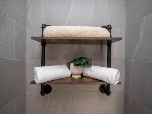 baño con 2 estanterías con toallas y una planta en Pass the Keys Stylish Croydon apartment - Central London links, en Croydon