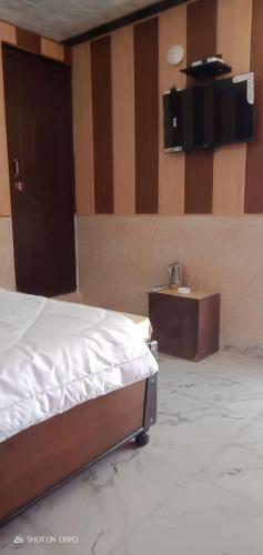 a bedroom with a bed and a table with a television at Hotel Akshat in Barkot