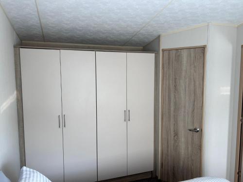 a bedroom with two white cabinets and a door at C&A Retreats in Gisburn