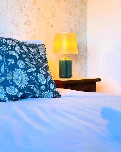 a bed with a blue pillow and a lamp on a table at Royal Reserve in Vál