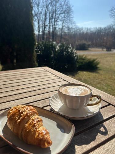 a cup of coffee and a croissant on a table at Royal Reserve in Vál