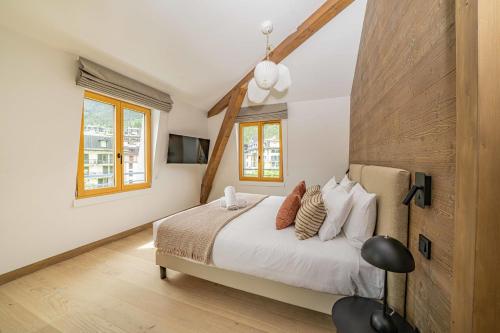 une chambre avec un lit avec des draps blancs et des oreillers dans l'établissement Paradisa Penthouse, à Chamonix-Mont-Blanc