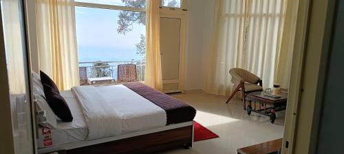 a bedroom with a bed and a large window at Barowalia villa Dalhousie in Dalhousie