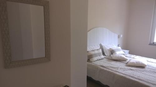 a bedroom with a bed with white pillows and a mirror at Il Porto dei Sognatori in La Spezia