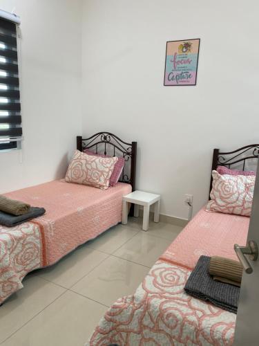 a bedroom with two beds and a table at My I-go Homestay in Shah Alam