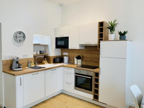 une cuisine avec des placards blancs et une horloge murale dans l'établissement Le Saint Claude, refait a neuf, à La Rochelle