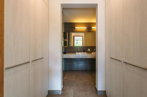 a hallway with wooden doors and a sink in a bathroom at Modern Apt - Direct Pool Access - Beaches 2 min in Mont Choisy