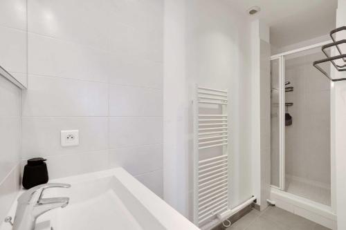une salle de bain blanche avec un lavabo et une douche dans l'établissement Elegant Apt - 1BDR 4P - Marais Place des Vosges, à Paris
