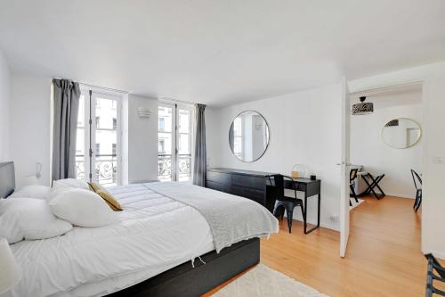 une chambre blanche avec un grand lit et un bureau dans l'établissement Elegant Apt - 1BDR 4P - Marais Place des Vosges, à Paris