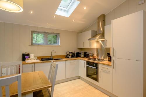 a kitchen with white cabinets and a table and a window at Woolverstone Marina and Lodge Park in Ipswich