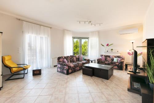 a living room with two couches and a tv at Solena in Tsikalariá